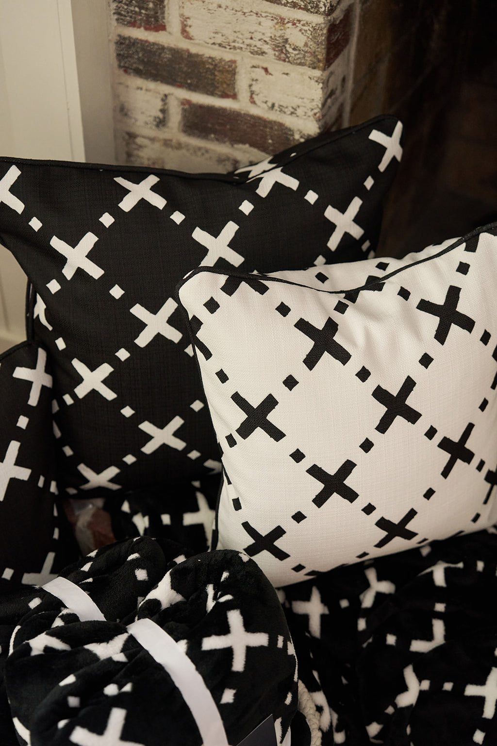 A man smiles and eats popcorn on a couch draped with The Paige Collection: Exes in Black Blanket, as sunlight streams through the window, creating a cozy setting.