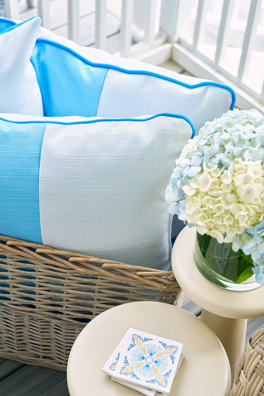 Two Spring Blue Blocks Oversized Pillows rest on a light sofa near a sunny window. Large green leaves and sheer curtains add a calming, modern feel to the bright, cozy space.