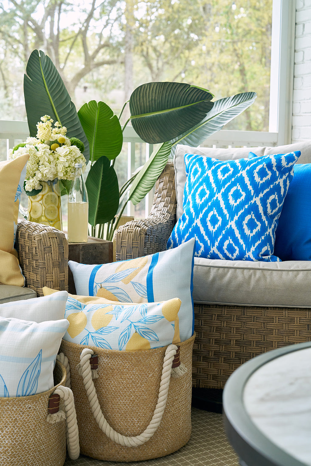 A person in a light blue shirt hugs the Blue Ikat Pillow, featuring a bold blue and white geometric pattern. Their face is partially out of frame.