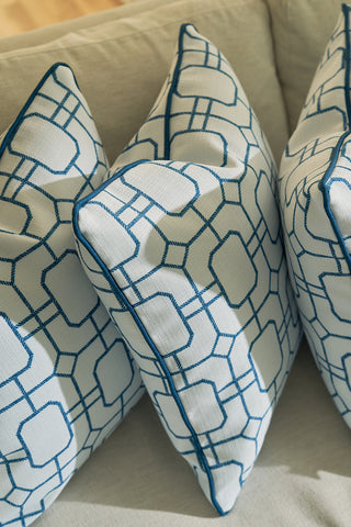 Three white throw pillows, including the Blue Lattice Oversized Pillow, are arranged diagonally on a light sofa. Bathed in natural sunlight, they bring a refreshing touch to your home decor.