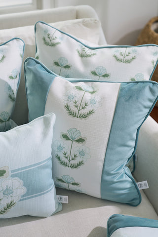 A light-colored couch is adorned with the Bee & Florals Collection: Victorian Floral in Blue Pillow, featuring blue and white designs of stylized flowers and green leaves, creating a serene and inviting atmosphere reminiscent of Sewing Down South elegance.