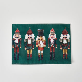 The Reversible Nutcracker Placemat Set of 4 features festive green placemats with five illustrated nutcrackers, including a central one in white and black—an ideal choice for holiday table decor.