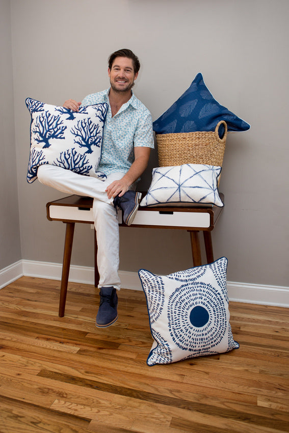 The Navy Coral Oversized Pillow from the Modern Collection adds coastal chic style, paired with blue and white pillows near a fireplace and a green potted plant.