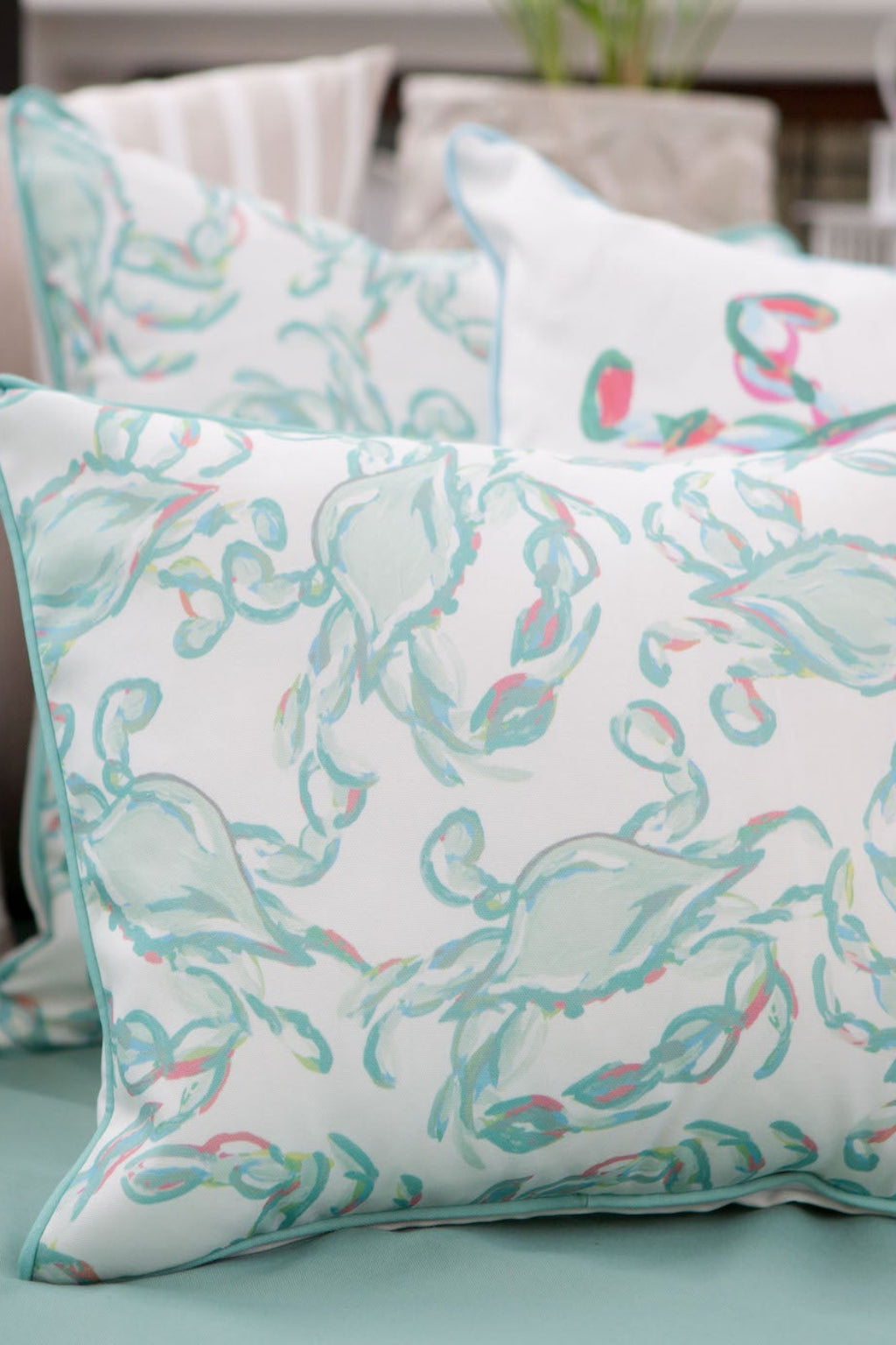 The Pastel Crab Craze Outdoor Lumbar Pillow, made with SDS Shield® Outdoor Fabric, features a Sewing Down South™ design of pastel pink and teal crabs on white, with a teal border on a light blue backdrop.