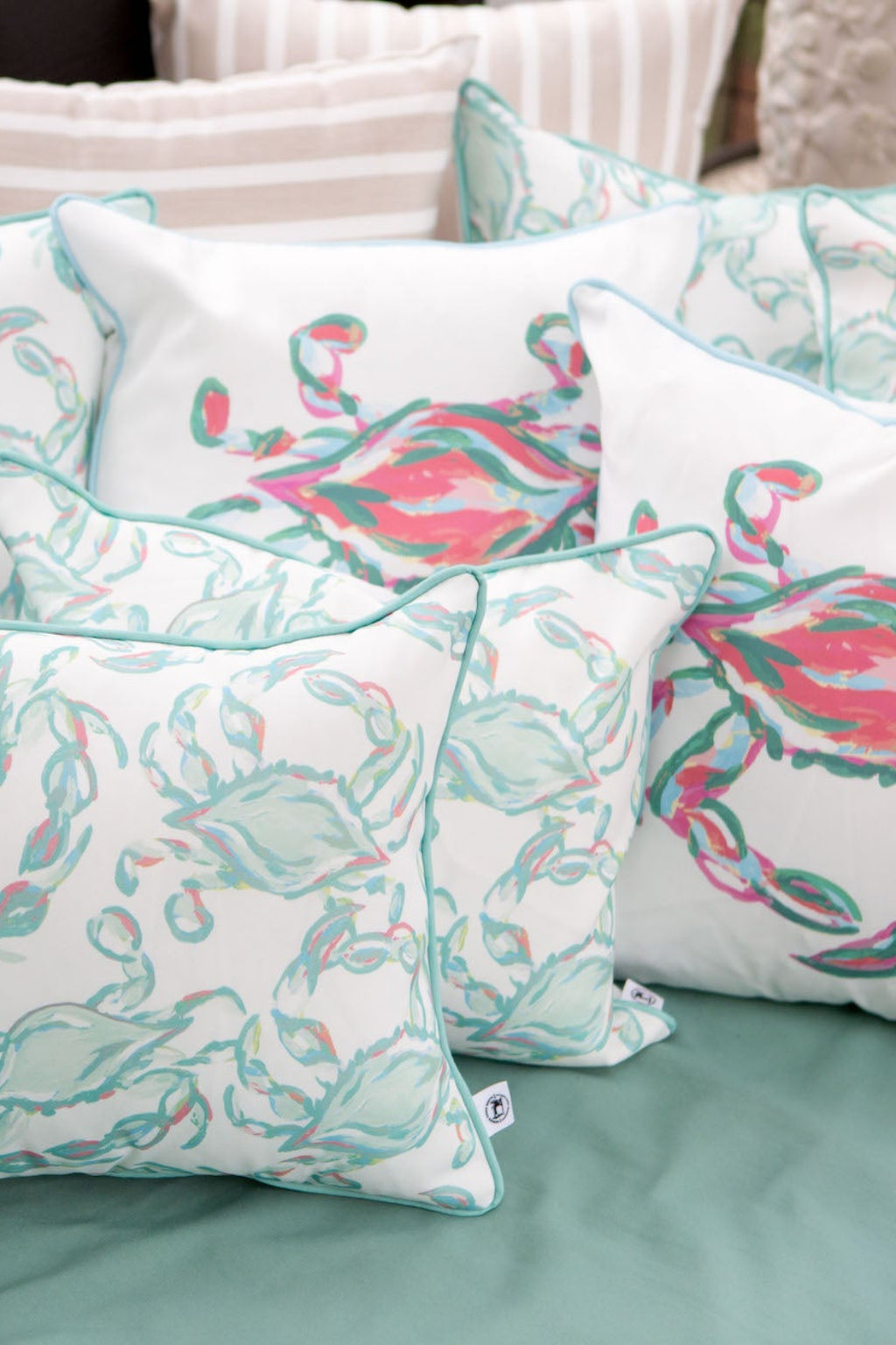 The Pastel Crab Craze Outdoor Pillow, a square white pillow with the Sewing Down South™ design, features a light blue and pink crab pattern. Made with durable SDS Shield® Outdoor Fabric, its perfect for marine-themed decor and serves as an ideal outdoor pillow against any backdrop.