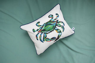 An Outdoor King Crab Lumbar Pillow with Navy, showcasing a colorful crab illustration, sits on a light green surface. Made with SDS Shield® Outdoor Fabric, it features dark blue edges and the Sewing Down South™ design tag on one side.