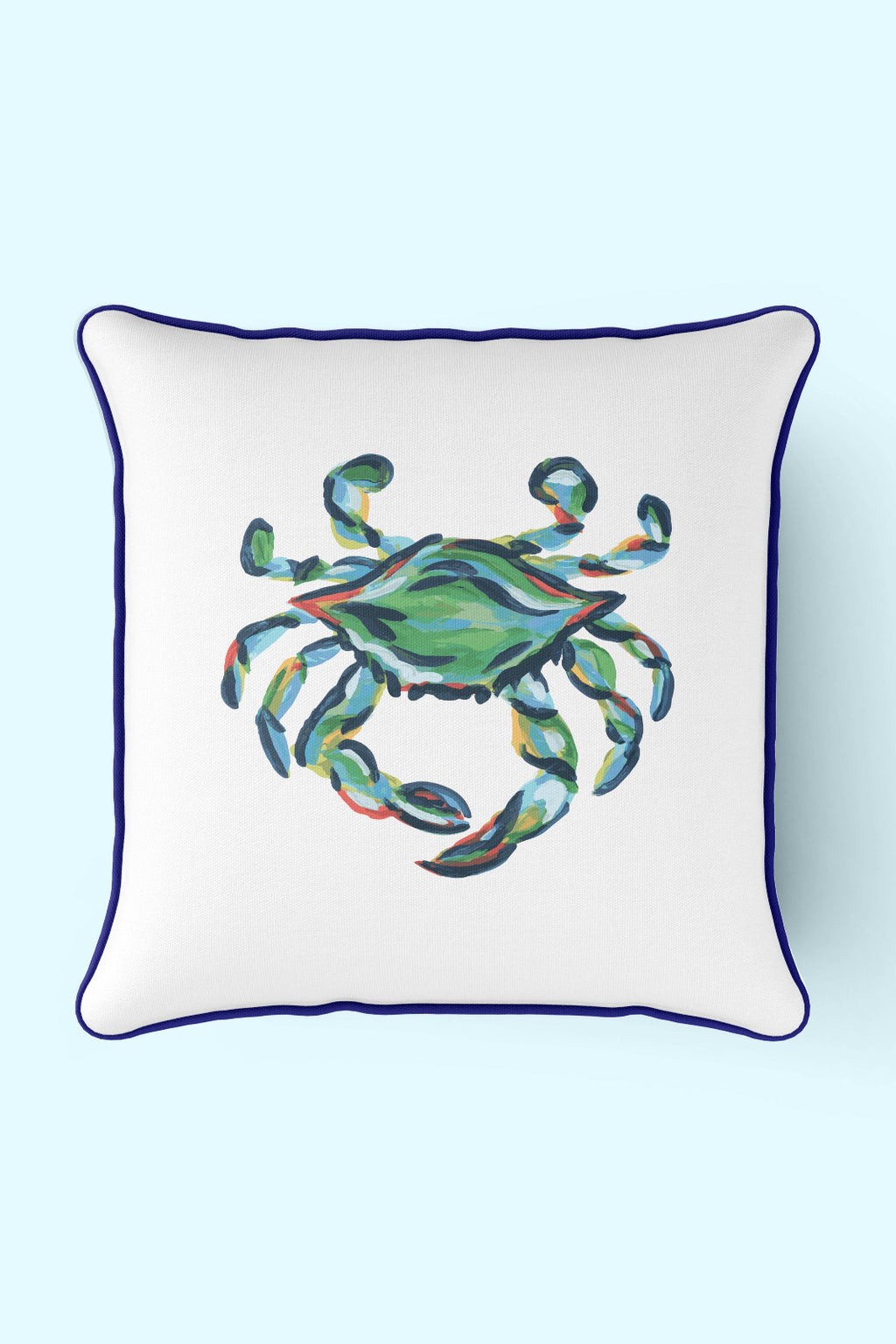 A man sits barefoot on a wooden porch, leaning against a white door. Wearing a blue sweater and white pants, he smiles while holding an Outdoor King Crab Pillow with Navy, made from SDS Shield® Outdoor Fabric with a painted crab design.