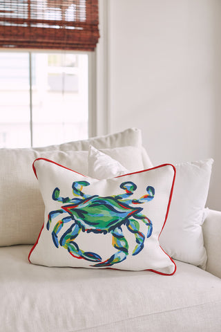 The Sewing Down South 16 x 20 Indoor Inserts pillow, boasting a vibrant multicolored crab design in green, blue, and red with red piping, adds a lively touch to a light-colored sofa by the window framed with wooden blinds. Made from non-allergenic fibers, it offers both style and comfort.
