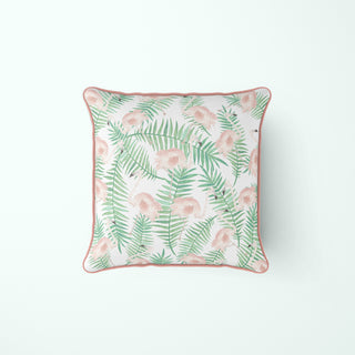 Square pillow with a white background, featuring a pattern of green fern leaves and pink watercolor-like flowers, finished with pink piping around the edges.