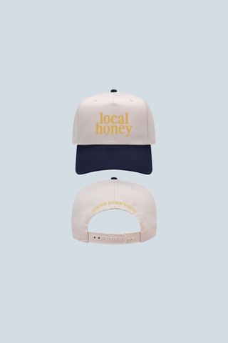 Front and back view of the Local Honey Embroidered Hat: white with a navy blue brim, "local honey" in yellow text on the front, and "SWING DOWN SOUTH" in yellow above the adjustable strap—ideal for beekeeping fans.