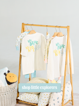 Clothing rack featuring t-shirts with "Bee Brave. Bee Kind. Bee You." design on them. Button that reads "Shop Little Explorers"