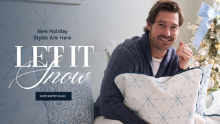 "Let it snow: Shop Wintry Blues, New Holiday Styles Are Here" 

Man holding a decorative pillow with snowflake pattern in front of a Christmas tree, promotional text for holiday styles.