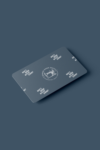 An E-GIFT CARDS design features a rectangular card with rounded corners, a blue-gray background, the phrase “WHAT’S WRITTEN DOWN SOUTH, STAYS WRITTEN DOWN SOUTH,” and a circular quill logo in a minimalist style.