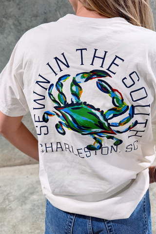 White t-shirt with colorful crab design and text on the back, worn by a person.
