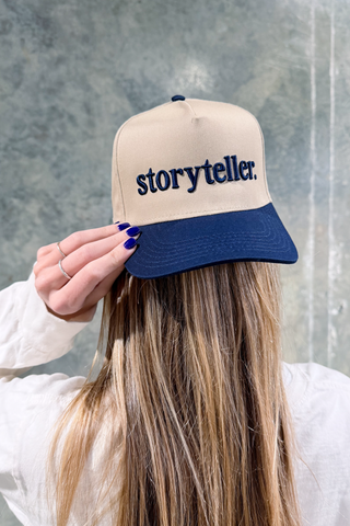 Person wearing a cap with 'storyteller' text against a gray background