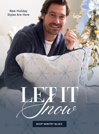 "Let it snow: Shop Wintry Blues, New Holiday Styles Are Here" 

Man holding a decorative pillow with snowflake pattern in front of a Christmas tree, promotional text for holiday styles.