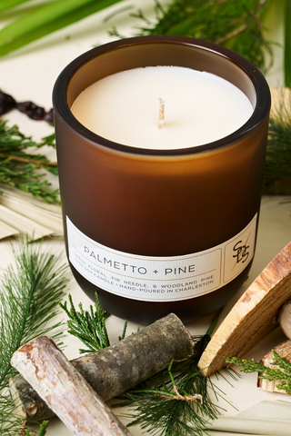 The Palmetto + Pine Signature Candle is a woodland pine soy candle, hand-poured in Charleston and presented in a charming brown container.