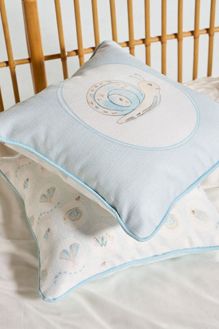 Two decorative Buggin’ Out Children’s Pillows with light blue trim rest on a white surface, featuring embroidered animals and playful shapes for a whimsical touch.