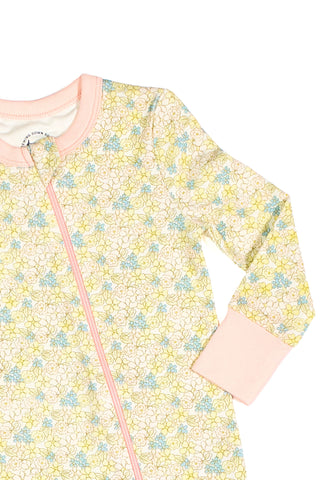 The Precious Petals Dream & Play Zipper Romper features long sleeves, a pink zipper and cuffs, and soft cotton modal fabric with pastel yellow, blue, and green floral prints on white.