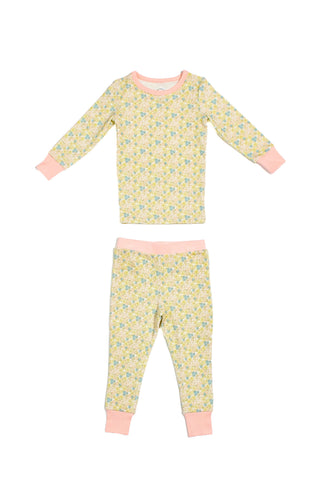 The Precious Petals Dream & Play Two Piece Set is a children’s long-sleeve pajama set featuring a yellow, blue, and green floral pattern. The cuffs, collar, and waistband are light pink. Made in the USA, this set is shown laid flat on a white background.
