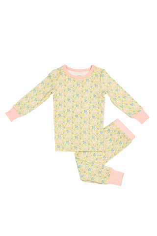 The Precious Petals Dream & Play Two Piece Set is a children’s pajama set featuring a floral pattern in yellow, blue, and green. It includes long sleeves and pants accented with light pink cuffs, neckline, and waistband. With its double-sided print, the charming design stands out from every angle. The set is displayed laid flat on a white background.