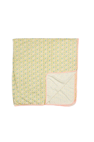 The Precious Petals Children’s Blanket features a rectangular shape adorned with a delicate yellow and blue floral pattern and is finished with a light pink trim. A folded corner reveals the double-sided design, showcasing similar charming prints on both sides.