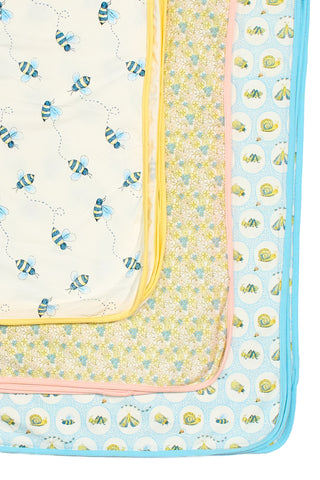 The Buzzin’ Around Children’s Blanket set includes four blankets, each with a unique design: buzzing bees, yellow flowers, cute chicks, and blue snails—perfect for kids with their colorful borders.