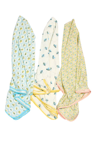 Three Buggin’ Out Children’s Blankets are displayed vertically: blue with ducks, white with blue birds and yellow trim, and yellow with a floral pattern and pink trim.