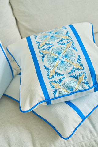 Two Line of Euro Blue Tiles Pillows with intricate blue and yellow embroidered designs and blue piping rest on a light sofa, radiating European elegance and a refined, coastal feel.