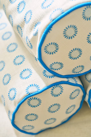 Three Calico Mini Floral Bolster Pillows, featuring vibrant blue flowers and blue piping, are stacked together. The fabric has a textured, woven look with striking circular floral patterns.