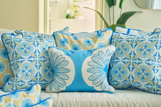 The Calico Scallop Lumbar Pillow, featuring blue, yellow, and white floral patterns, is arranged on a light sofa to create a fresh and cheerful coastal summer vibe.