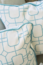 Two white pillows featuring a geometric blue pattern and blue piping are placed on a light surface, partially overlapping—perfect as Beach Lattice Oversized Pillows to bring a chic coastal flair to your space.