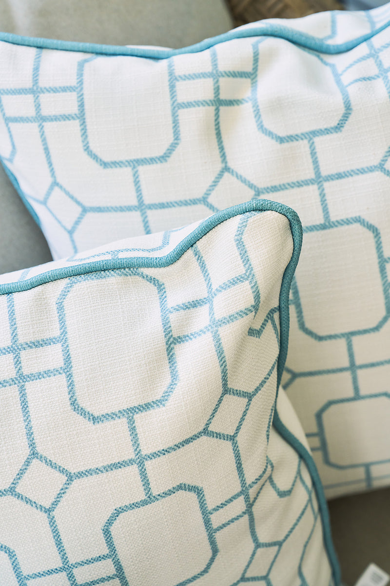 Two white pillows featuring a geometric blue pattern and blue piping are placed on a light surface, partially overlapping—perfect as Beach Lattice Oversized Pillows to bring a chic coastal flair to your space.