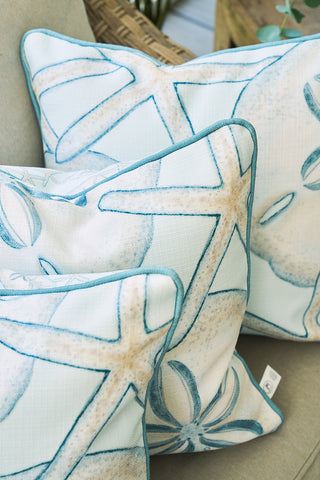 The Beaches Pillow—featuring blue and beige sand dollar and starfish prints—adds coastal charm and seaside nostalgia to any neutral outdoor chair.