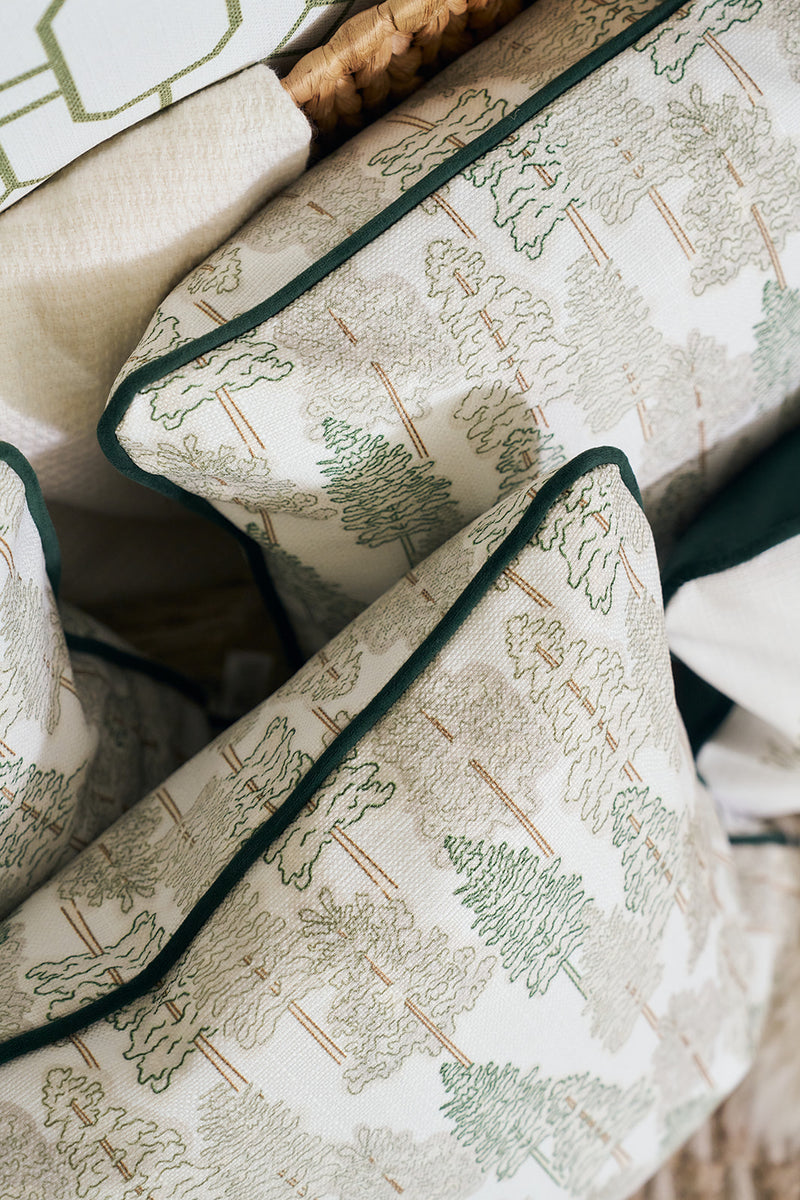 A close-up of the Christmas Tree Farm Pillow, featuring a green and beige tree pattern with dark green piping, arranged on a light-colored surface.