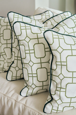 The Green Holiday Lattice Oversized Pillow, with a white cover, green geometric pattern, and dark green piping, is arranged with two similar pillows on a light sofa for festive holiday decor.