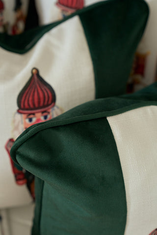Close-up of decorative pillows in dark green and white, including the Nutcracker Stripe Pillow in Spruce featuring a toy soldier face with a red hat and blue eyes partially visible.