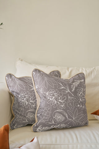 Two Holiday Harvest Pillows with white floral patterns and beige piping rest on a light beige sofa, perfect for Southern decor. Part of two autumnal throw pillows are visible in the foreground.