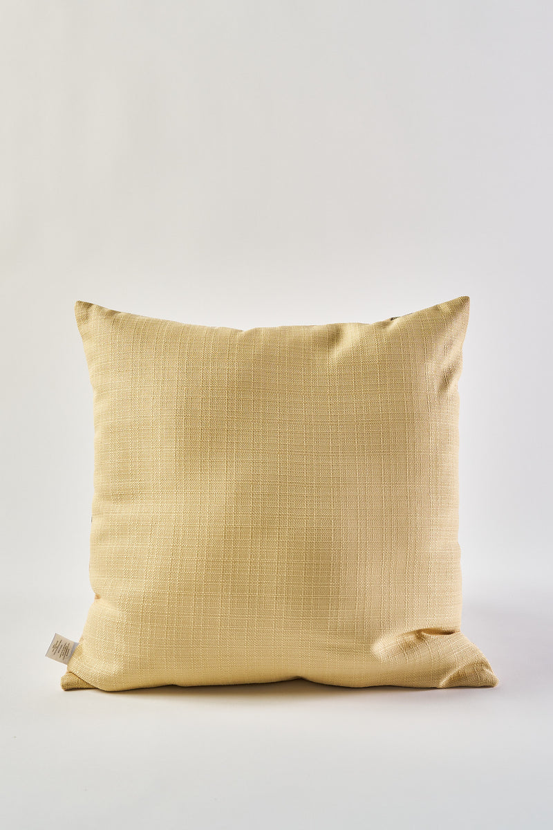The Fall Pear Tree Pillow, a square accent pillow in light yellow with a rustic textured finish, stands upright against a plain white background. A small fabric tag is visible on the lower left side.
