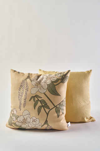 The Fall Pear Tree Pillow, with a floral pattern of green leaves and white flowers, sits in front of a solid light yellow pillow on a neutral background—making it an ideal autumn decor accent.