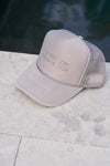 A light gray mesh-back trucker hat with IM NOT A FISH and a snorkel mask drawing on the front. This adjustable snapback cap, known as the Im Not A Fish Hat, is set against a pale stone surface with a dark, blurred background.