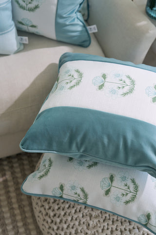Two decorative pillows from the Bee & Florals Collection: Victorian Floral Stripe Pillow, with teal edges and green-teal designs, sit on a beige sofa. They feature a Sewing Down South® floral pattern on white. Below is a textured, light-colored rug.