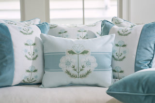The Bee & Florals Collection: Victorian Floral Stripe Lumbar Pillow by Sewing Down South® is part of a decorative pillow set on a light-colored sofa near a window. The pillows, in blue and white with floral embroidery, are made in the USA and bask in soft, natural light.