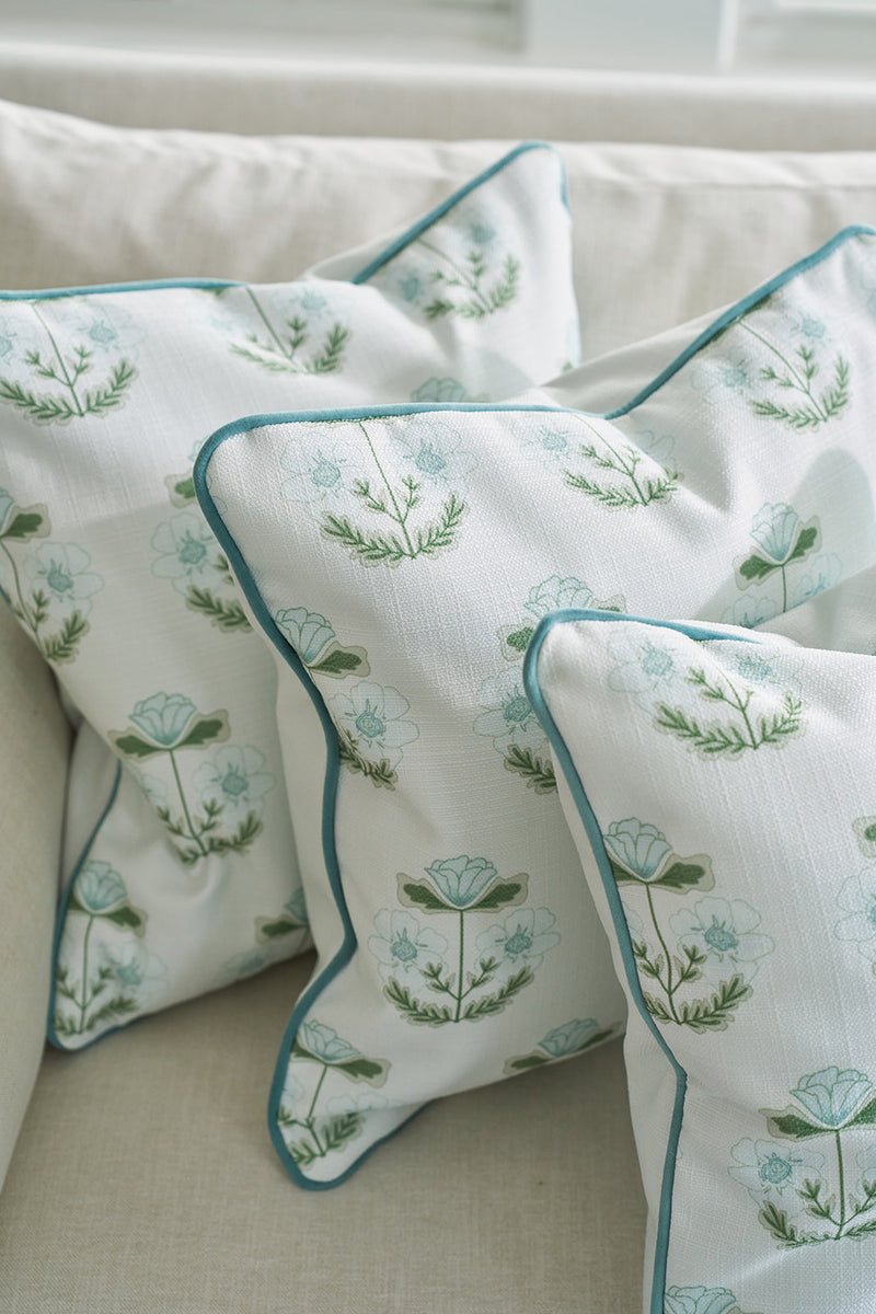 Three Bee & Florals Collection: Victorian Floral in Blue pillows grace a light sofa, showcasing a charming light blue flower and green leaf pattern with blue trim, creating an inviting scene that perfectly blends classic charm with modern elegance.