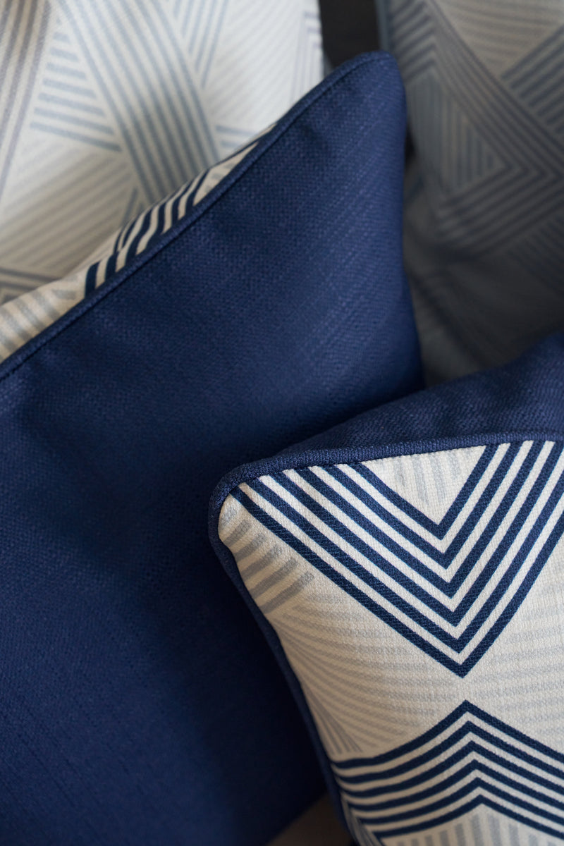 A close-up of decorative pillows, including the Mod Geo Diamond in Navy Pillow with blue geometric chevron-like patterns, all neatly arranged to add a touch of Southern aesthetic decor.