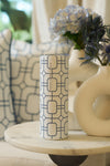 A Blue Lattice 20oz Tumbler from Sewing Down South rests on a marble table beside a cream vase with blue and white flowers, with a cushion featuring a matching geometric design in the background.