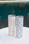 Two tall stainless steel tumblers with lids sit poolside. One 20oz cup is cream with pink flamingos, the other is the Blue Lattice 20oz Tumbler, white with a blue geometric pattern. Both have a no sweat exterior and SEWING DOWN SOUTH label.