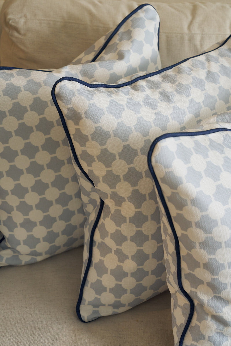 Three Oversized Mod Dot Grid Pillows with an exclusive hand-drawn light blue and white pattern plus dark blue piping rest on a beige sofa, adding a stylish modern Southern decor touch.