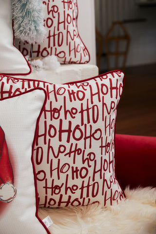 A festive Christmas pillow with red Ho Ho Ho text on white sits on a fluffy surface beside a Vintage Stitch Santa Pillow and other holiday pillows from Sewing Down South.