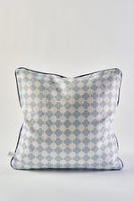 The Oversized Mod Dot Grid Pillow is a square decorative accent inspired by modern Southern decor, featuring a light blue and white geometric hand-drawn pattern, piped edges, and a small fabric tag on the side against a plain white background.